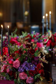 an arrangement of flowers and candles on a table