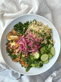 a white bowl filled with meat, vegetables and grains on top of a table cloth