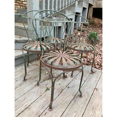 three metal chairs sitting on top of a wooden deck