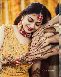 a woman in yellow dress holding hands with henna on her face