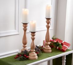 three candles sitting on top of a table next to a christmas wreath and gift box