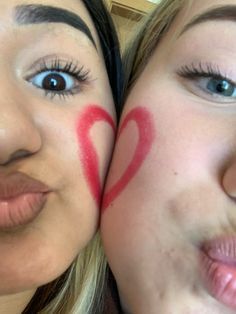 two girls with painted faces are posing for the camera and one has her face painted like a heart