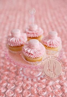 three cupcakes are sitting on a pink tablecloth