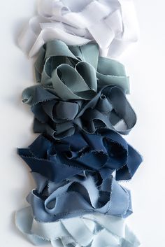 several different colors of fabric on a white surface with one blue and the other grey