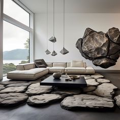 a modern living room with large rocks on the floor and an unusual rock sculpture hanging from the ceiling