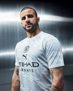 a man with tattoos standing in front of a metallic background