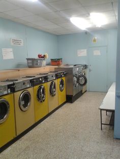 a row of washers and dryers in a room with light blue walls on the ceiling