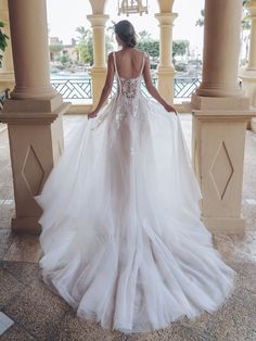 a woman in a wedding dress is standing under an archway and looking at the water