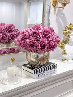 pink roses in vases sitting on top of a table next to a mirror and candle