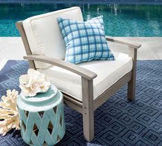 a chair sitting on top of a blue rug next to a pool with water in the background