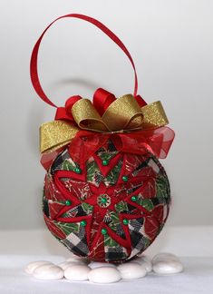 a christmas ornament hanging from a red ribbon on top of some white balls