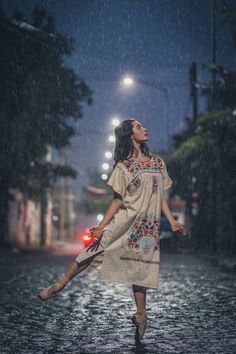 a woman is walking in the rain holding an umbrella and looking up into the sky