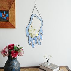 a vase filled with flowers on top of a wooden table next to a book and clock