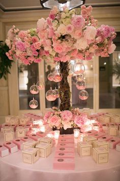 a table topped with lots of pink flowers next to a tall vase filled with bubbles