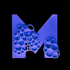 the letter m is made up of blue bubbles and water droplets on it's surface