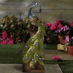 a statue of a peacock with feathers on it's head in front of flowers