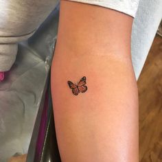 a small butterfly tattoo on the arm