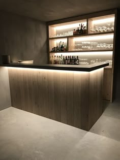 an empty bar is lit up with dim lights and bottles on the shelves behind it