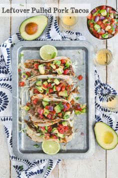 an overhead shot of tacos with avocado, salsa and limes on the side