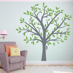 a living room with a chair and tree wall decal