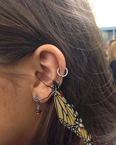 a close up of a person's ear with a butterfly attached to the ear