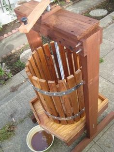 a wooden bucket sitting on the ground next to a trash can with metal straps around it