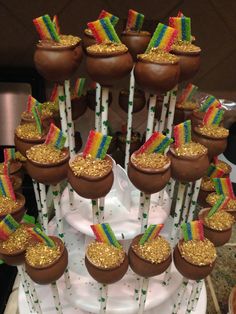 there are many candy pops with rainbow decorations on the top and one is filled with gold sprinkles