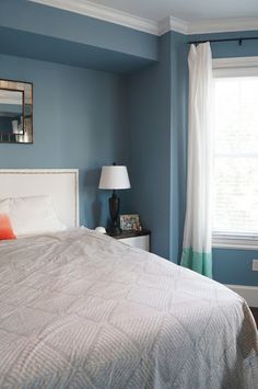 a bedroom with blue walls and white bedding