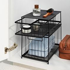 a black metal cage with towels and other items in it next to a brown bag