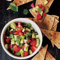 a white bowl filled with fruit and veggies next to tortilla chips