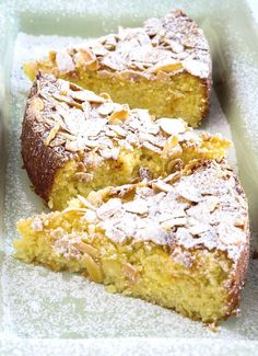 two pieces of cake sitting on top of a pan covered in powdered sugar and almonds