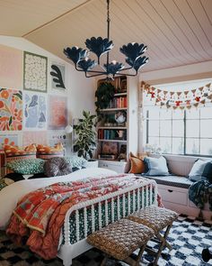 a bed room with a neatly made bed and lots of pillows on the floor next to a window