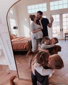 a man taking a photo of himself and his family in front of a large mirror