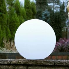 a white round object sitting on top of a stone wall next to a garden statue