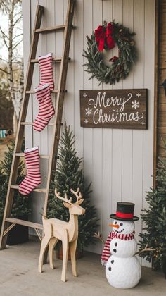 a snowman next to a ladder and christmas decorations on the side of a house