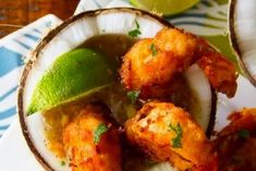 some food is in a white bowl on a table with limes and a spoon