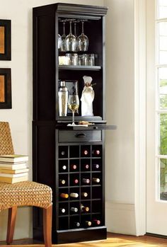 a wine rack with bottles and glasses on it in front of a chair next to a christmas tree