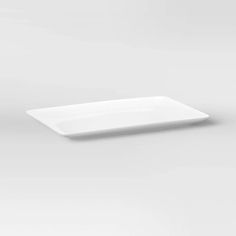 an empty white plate sitting on top of a gray surface with no one around it