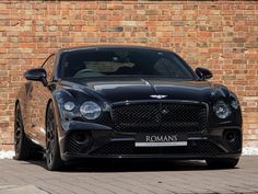 a black car parked in front of a brick wall with the name romans on it