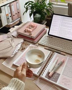 a person sitting at a desk in front of a laptop computer with papers and notebooks on it