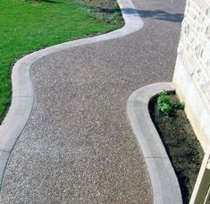 a driveway with gravel and grass next to a building