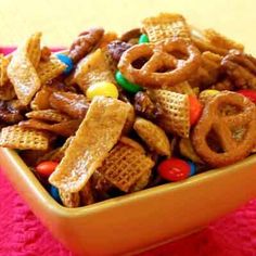 a yellow bowl filled with cereal and pretzels