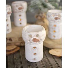 some white vases sitting on top of a wooden table next to a potted plant