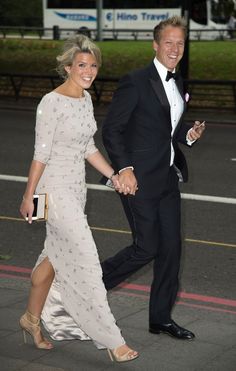 a man and woman in formal wear walking down the street holding each other's hands