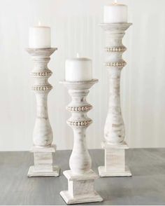 three white candles sitting on top of a wooden table