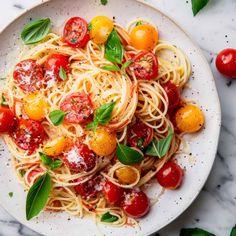 a white plate topped with pasta and cherry tomatoes