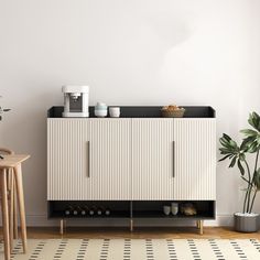 a white and black cabinet with shoes on it in a room next to a potted plant