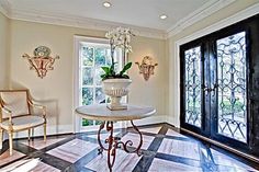 a room with two chairs, a table and a potted plant in the center