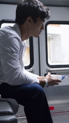 a man sitting on a train looking at something in his hand