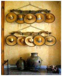 several hats are hanging on a wall near vases and jars with chains attached to them